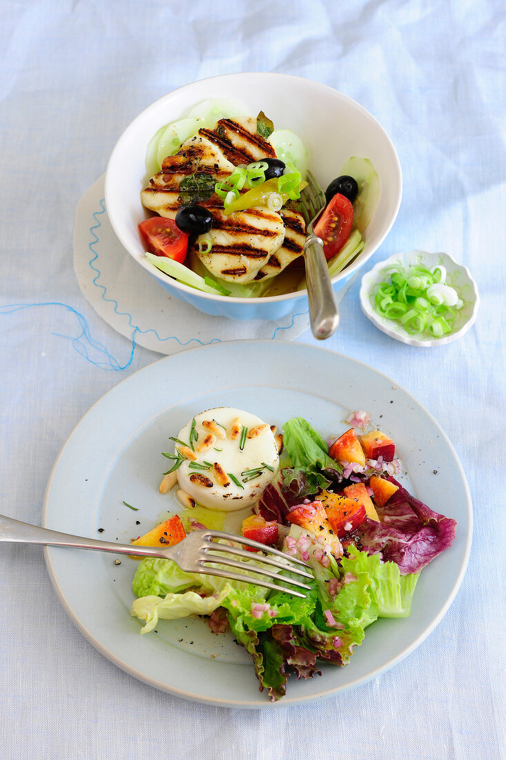 Greek salad with halloumi on plate and goat cheese salad in bowl, low GI diet food