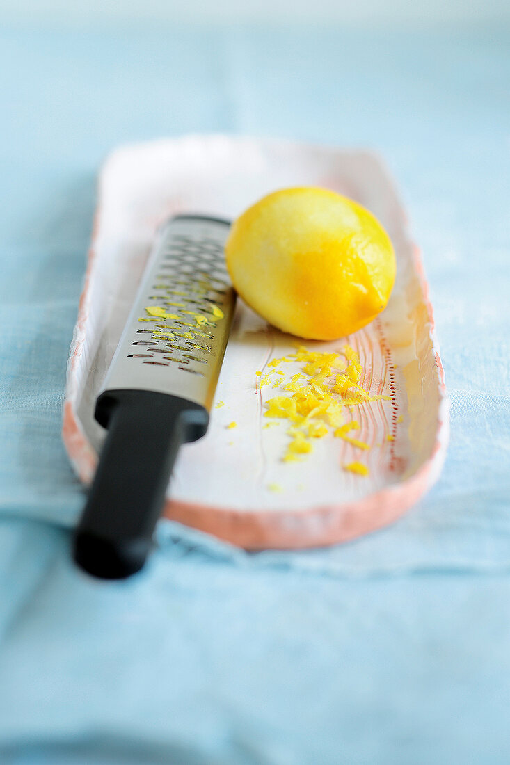 Lemon and grater on plate