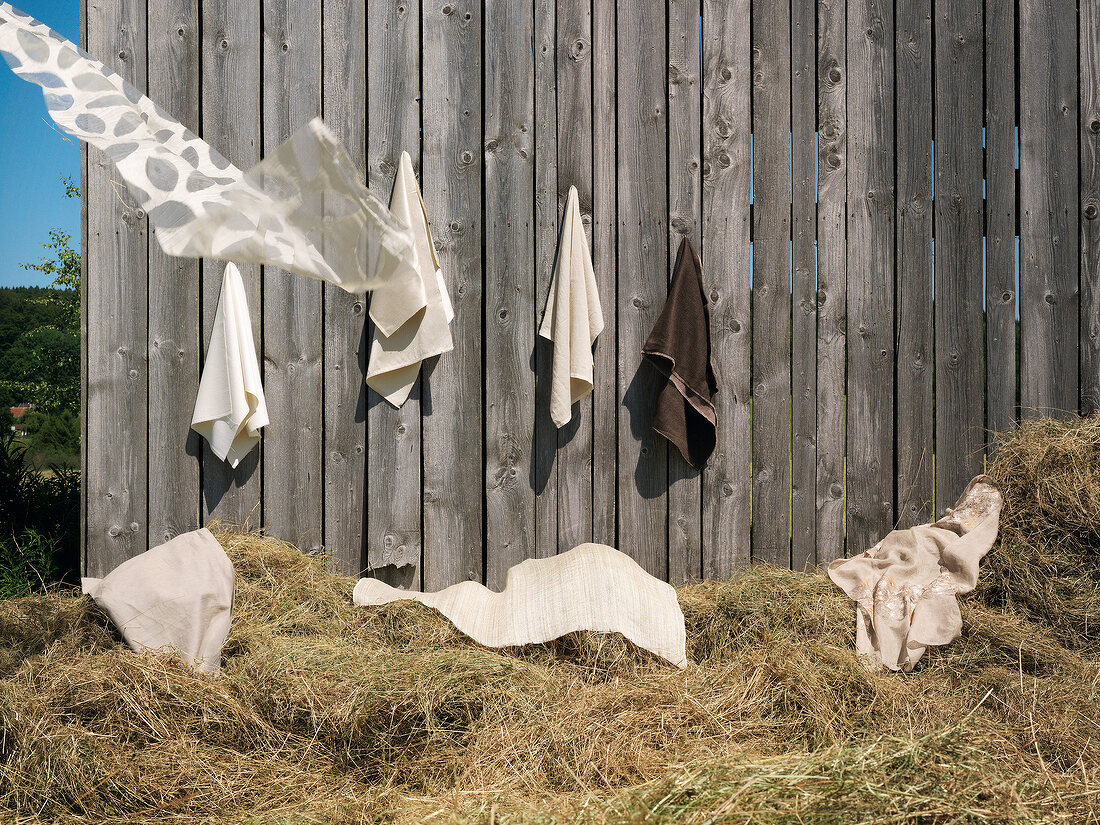 Different types of clothes on hay in front of wooden hut