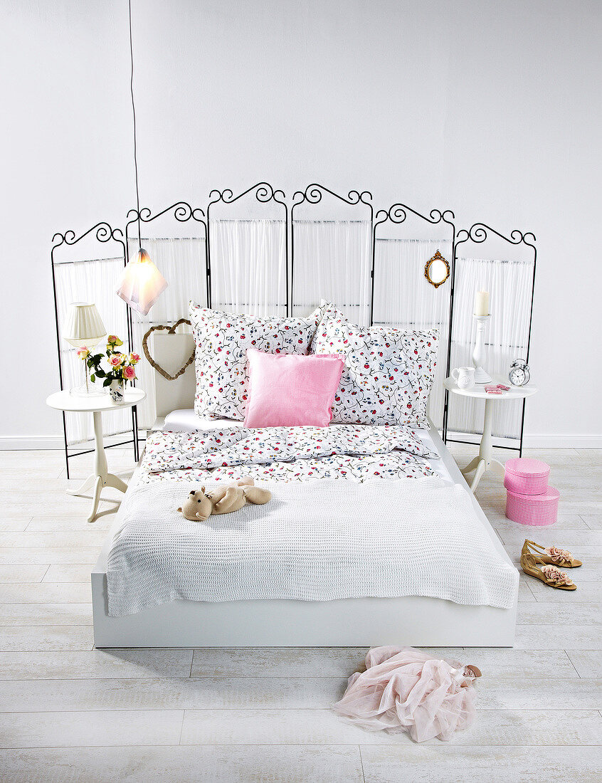 Bedroom with pink and white cushions, room dividers, bed, and side table