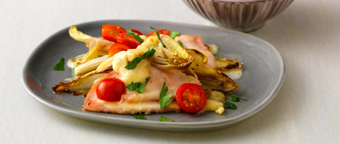 Baked endive with cherry tomatoes on plate