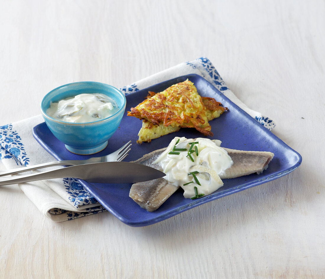 Herring with hash browns and yogurt sauce on plate