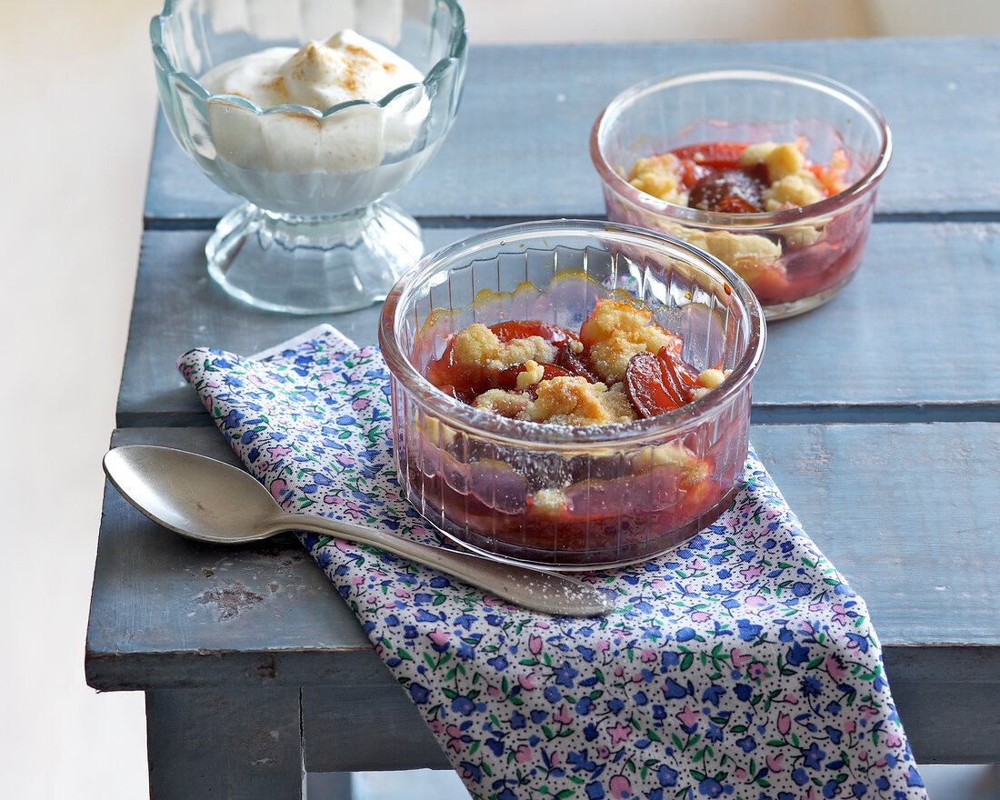 Plum crumble with cinnamon cream in glass bowls