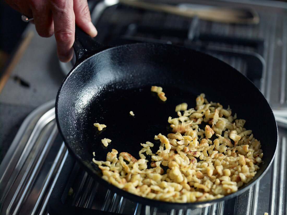 Close-up of onions fried in pan while preparing spaetzle, step 1