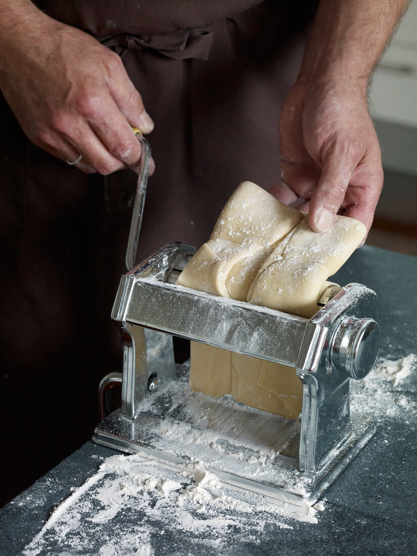 Close-up of dough being put through pasta maker while preparing pasta, step 2