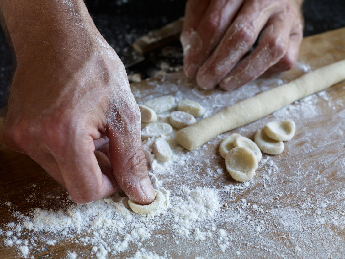 Close-up of hand pressing dough while preparing orecchiette pasta
