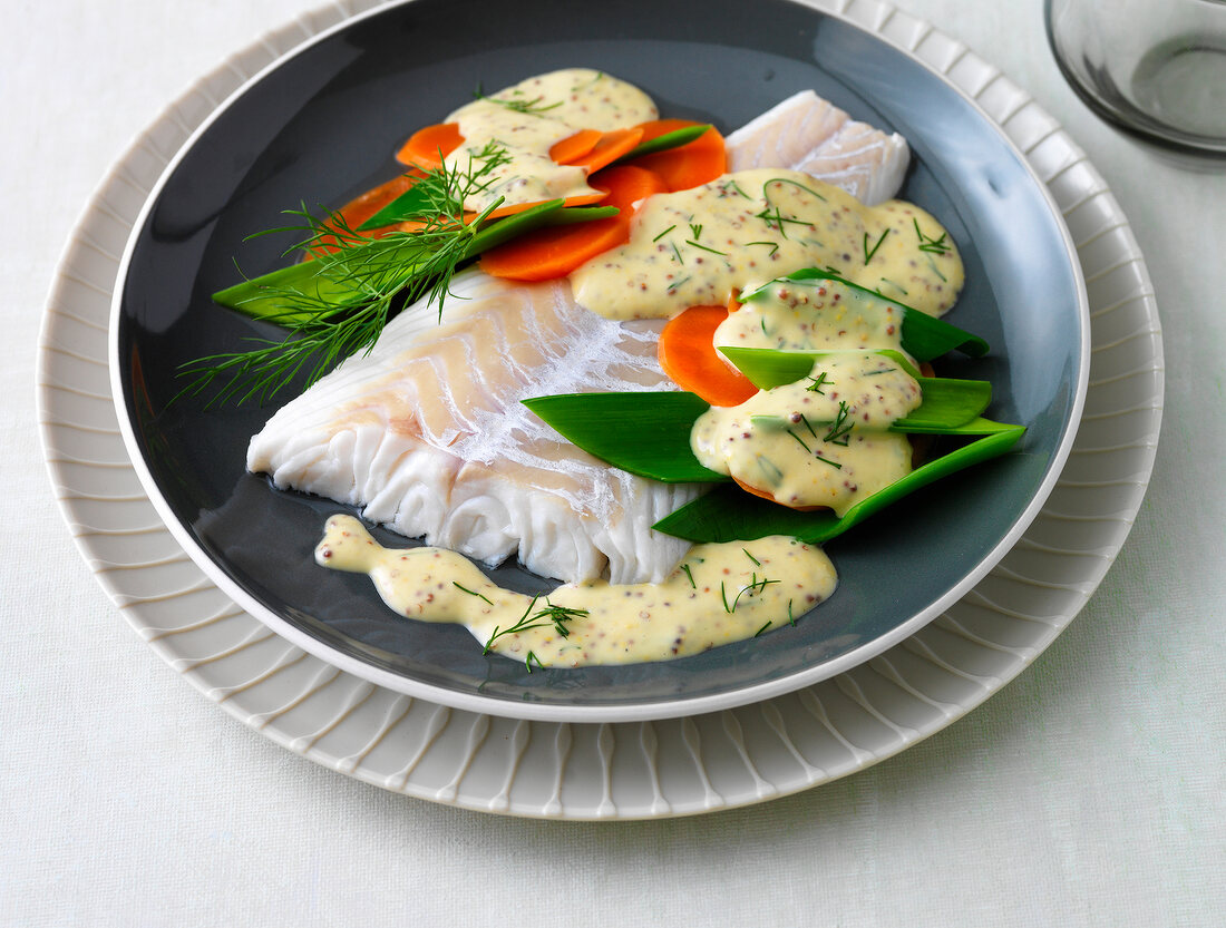 Cod fillet with mustard sauce and dill on plate