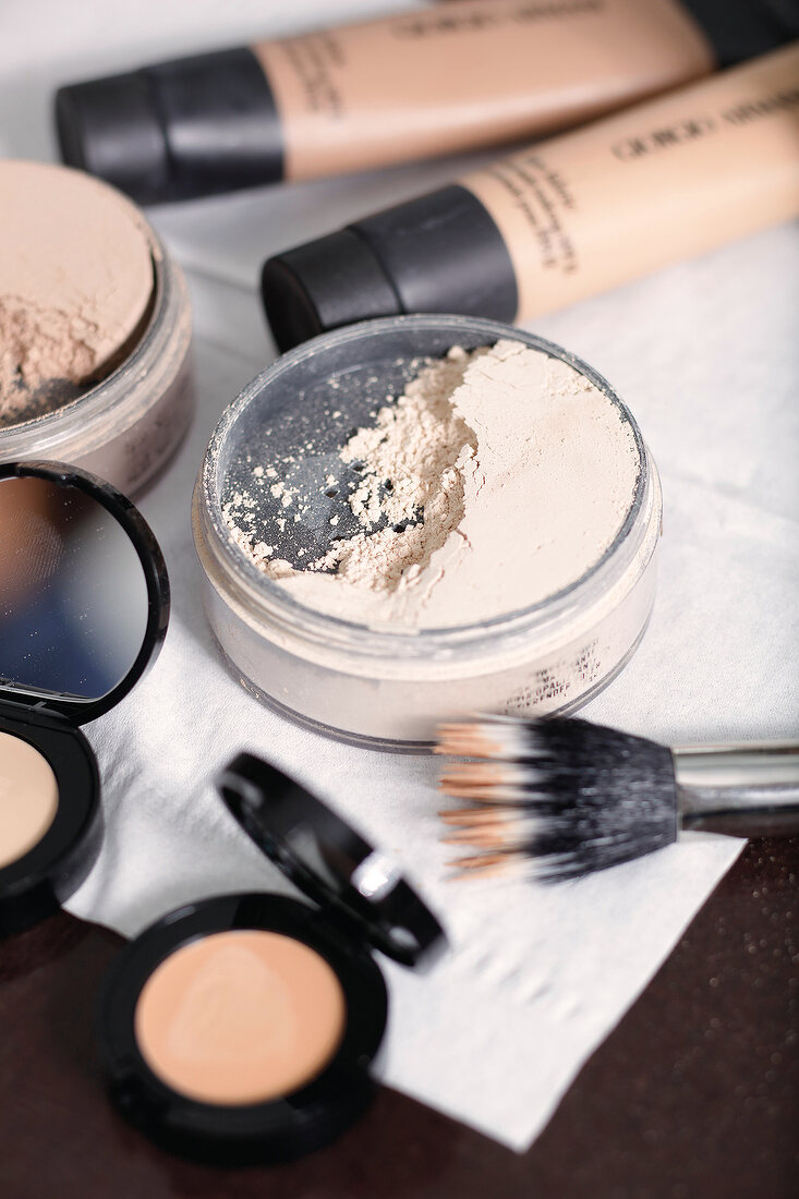 Close-up of make-up powder, concealers and brushes on table