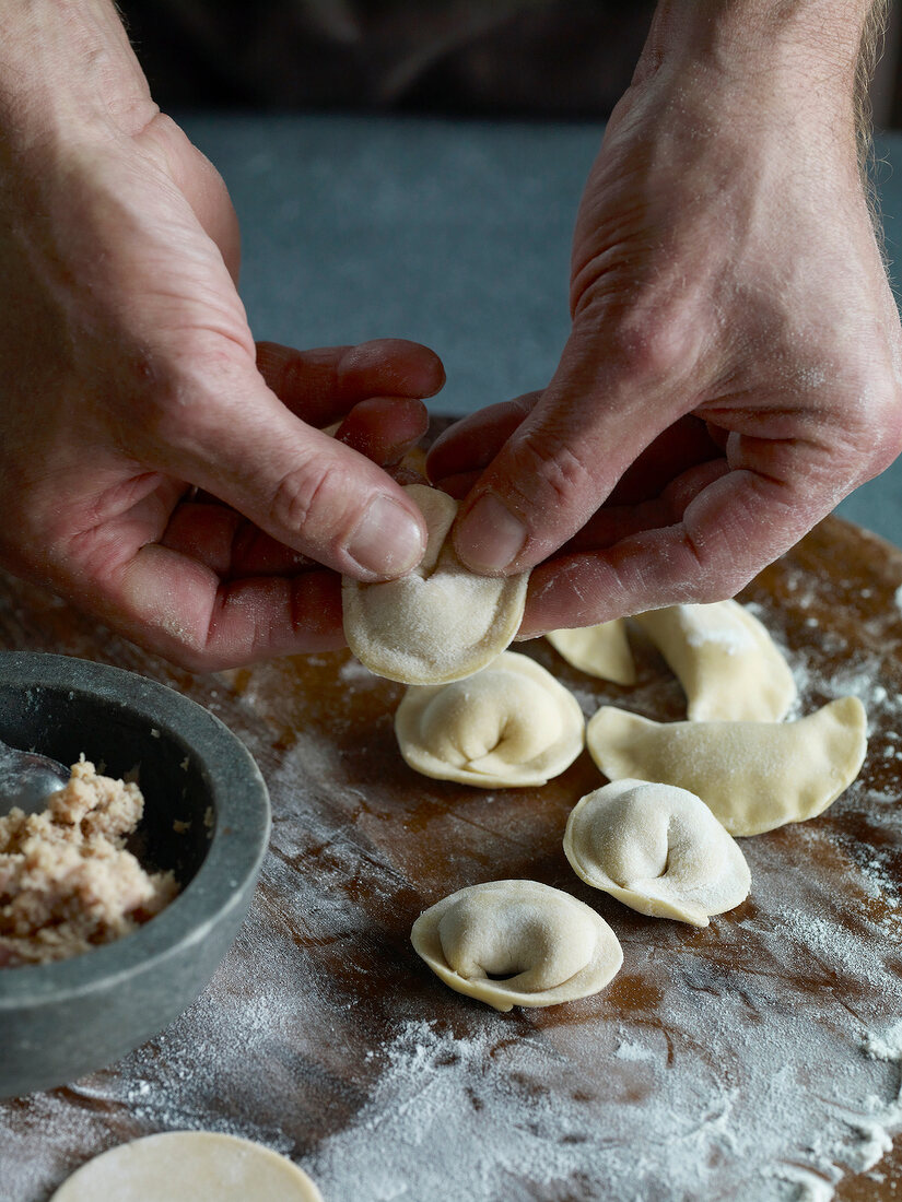 Close-up of dough being pressed for preparation of tortellini pasta, step 3