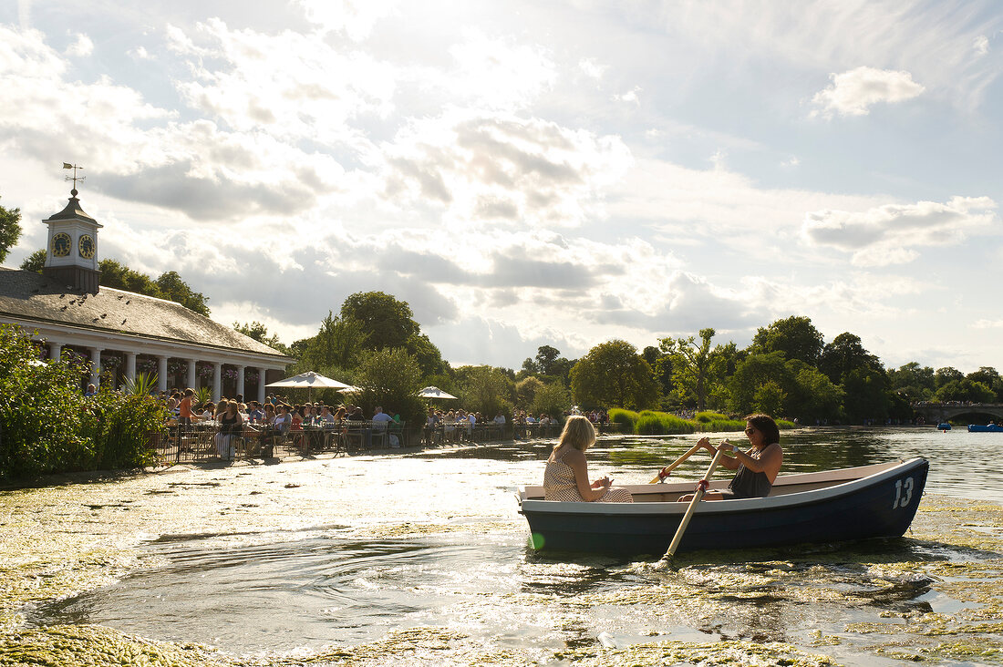 Two women in boat on Serpentine Lake, Hyde Park, London, UK