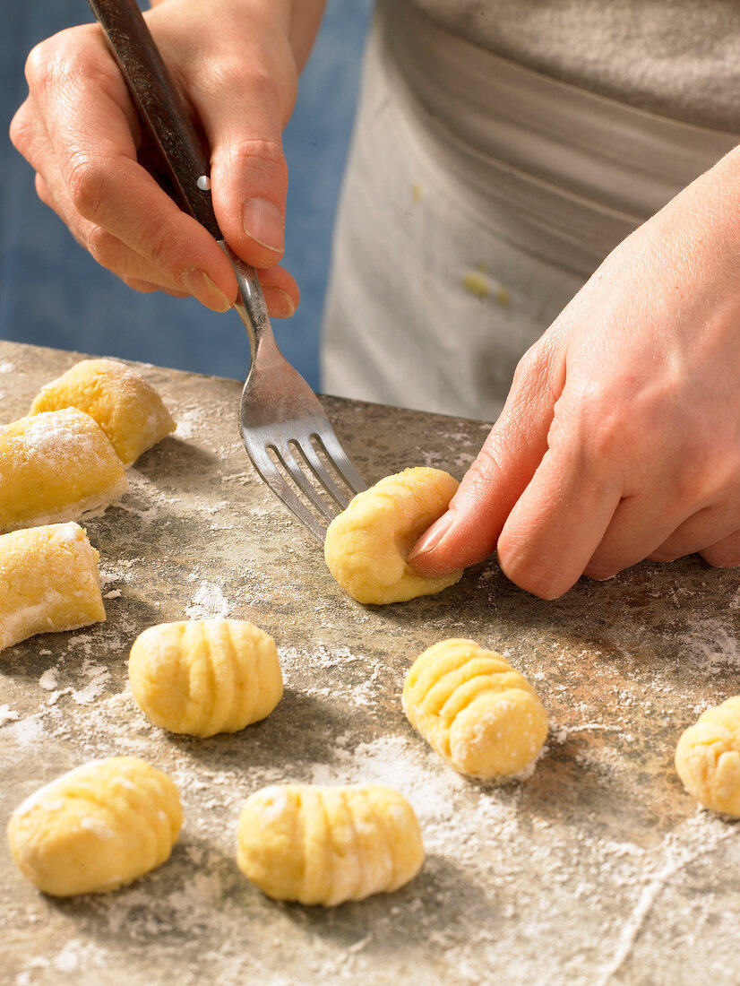 Close-up of hand pricking dough for preparing gnocchi