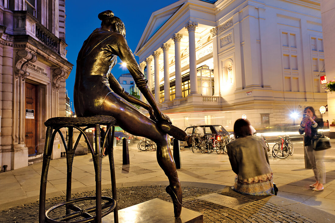 Two women photographing in front of sculpture, Covent Garden, London, UK