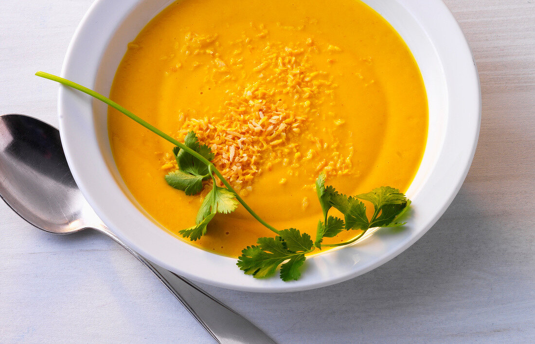 Carrot and coconut soup with herb in bowl