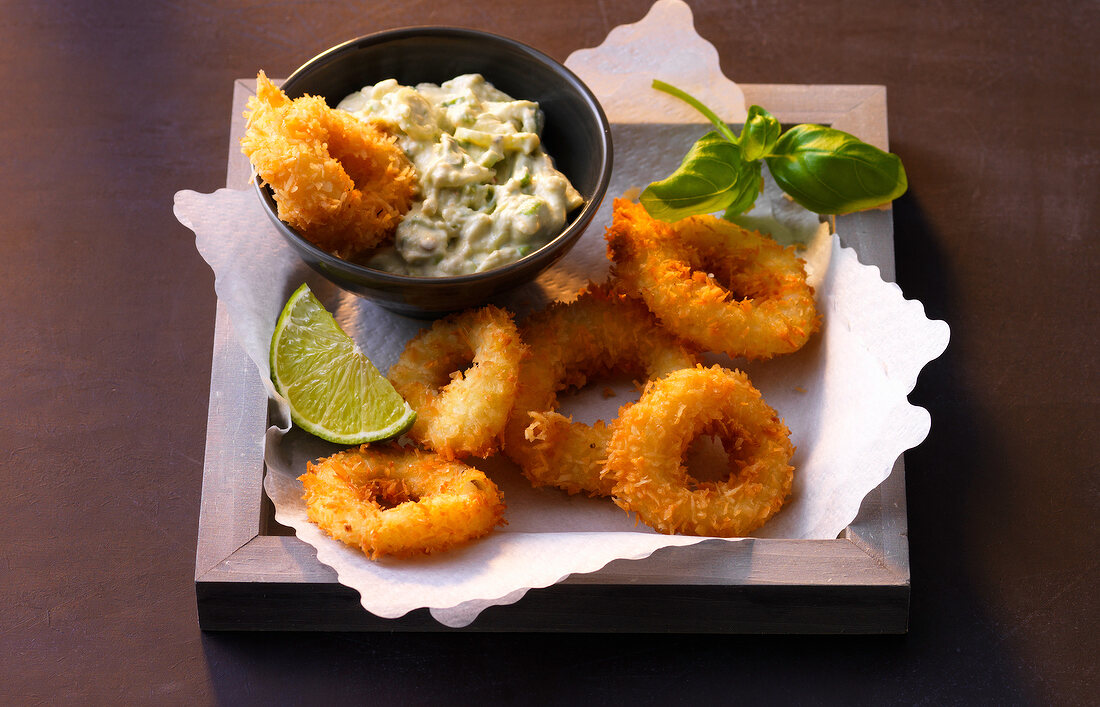 Avocado dip with coconut calamari and lime on serving tray
