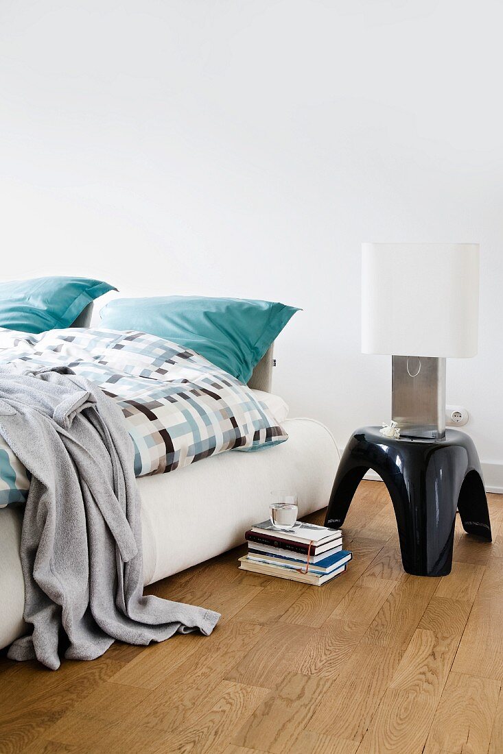 Upholstered bed with stool as table for bedside table lamp