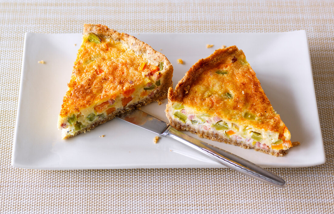 Two pieces of bacon and vegetable quiche on plate