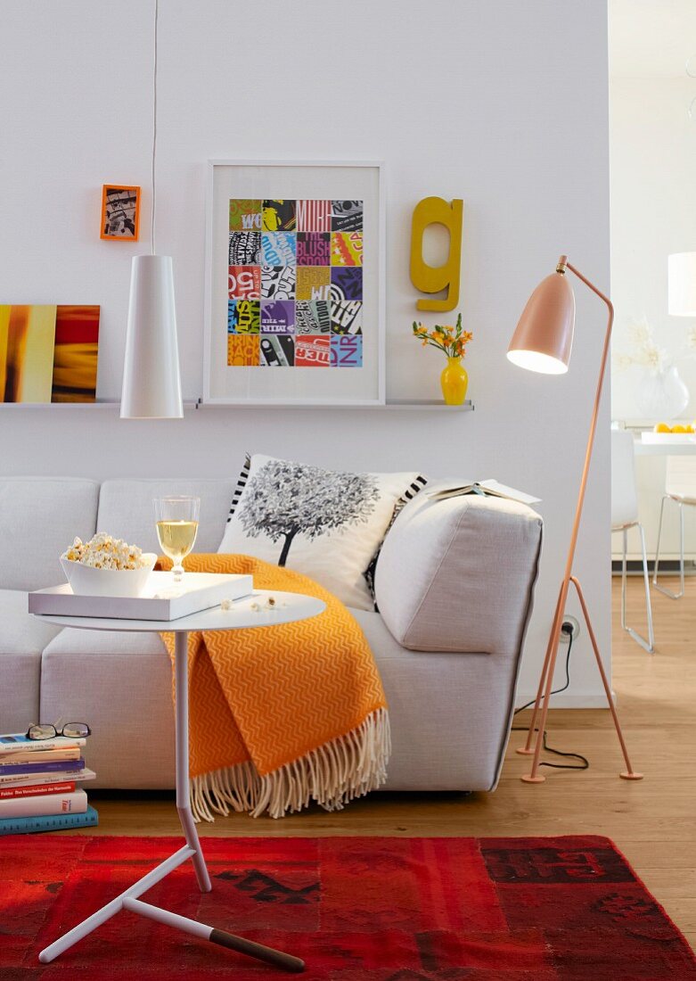 A living room with a sofa, a floor lamp, a side table and a pendant lamp