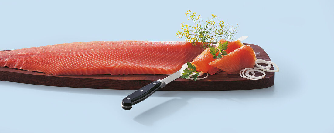 Smoked salmon with knife on wooden board
