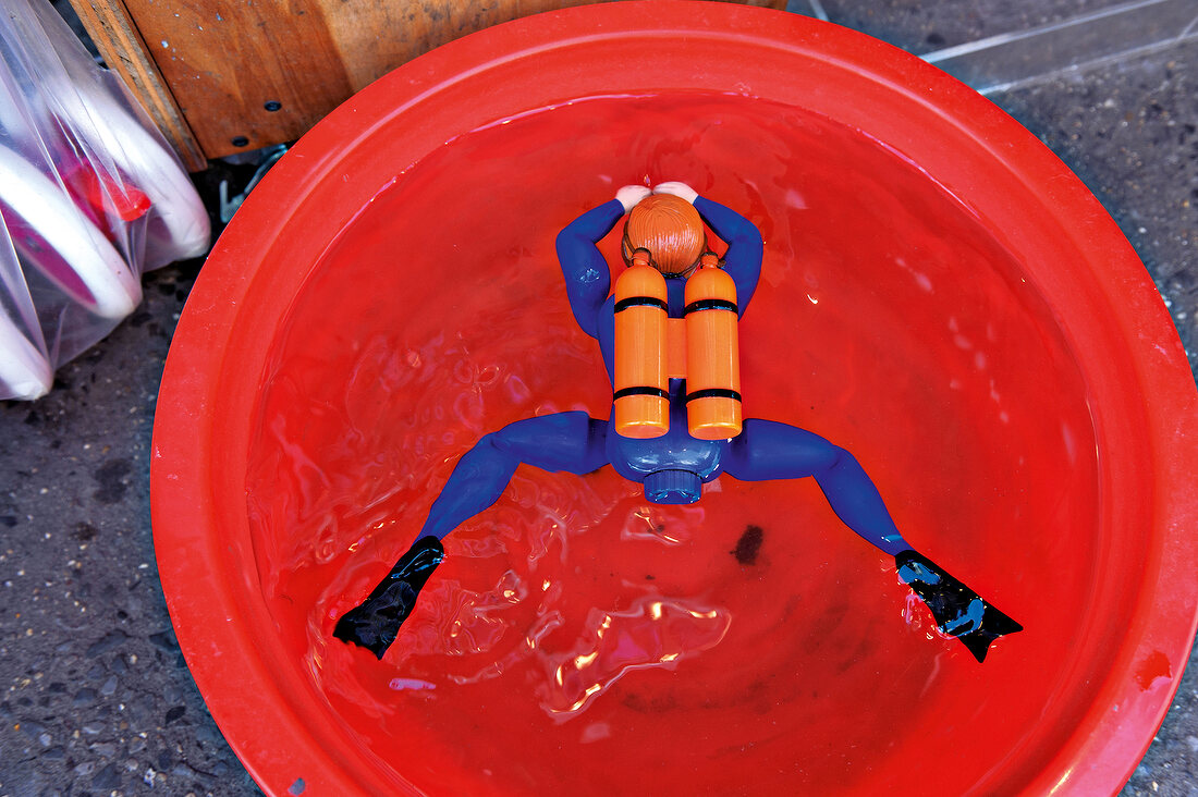 Toy scuba diver floating in red tub, Brooklyn, New York, USA