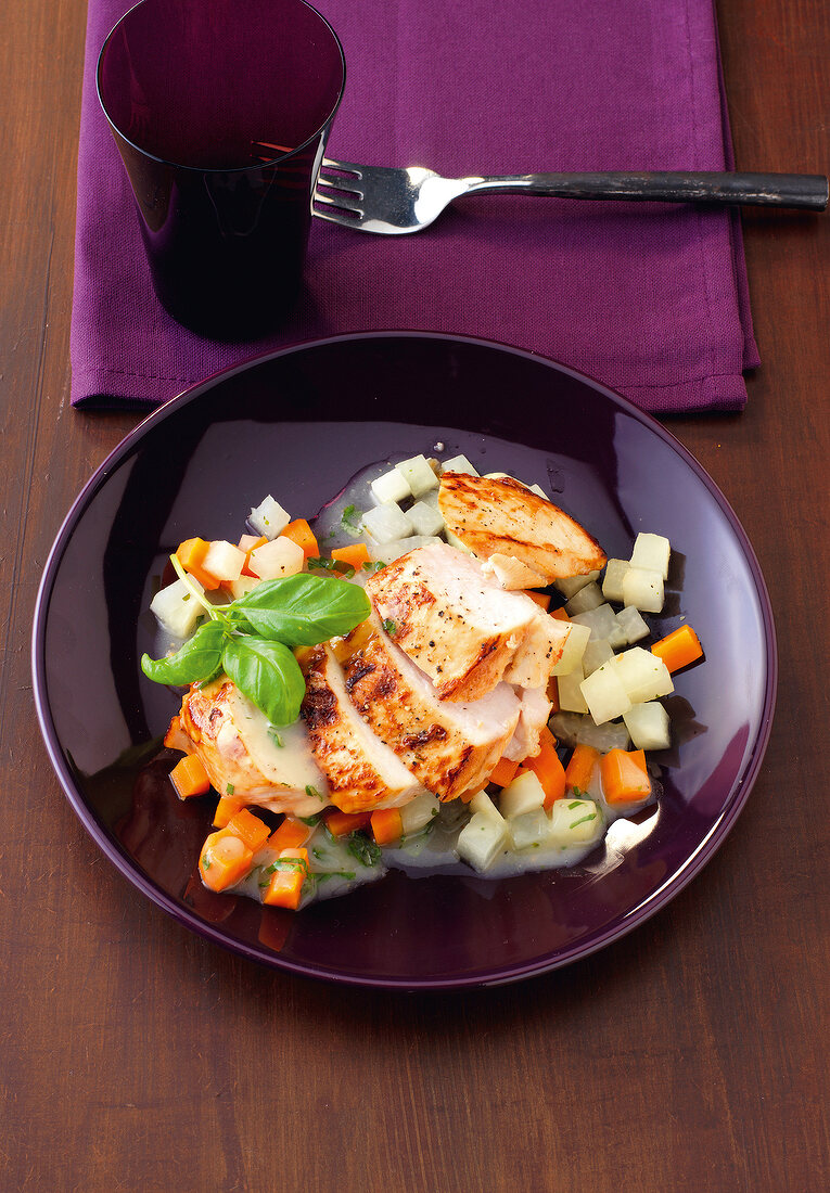 Marinated chicken breast garnished with diced vegetables and herb on plate