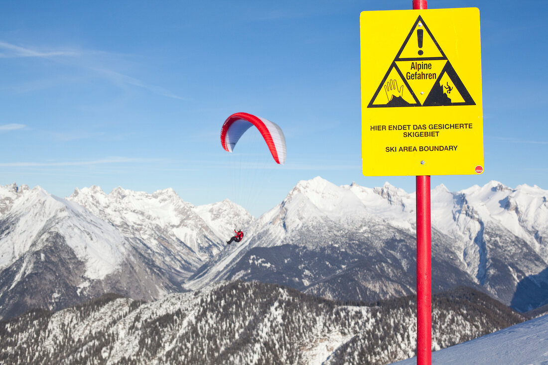 Man paragliding between snow mountains at Leutaschtal, North Tyrol, Italy