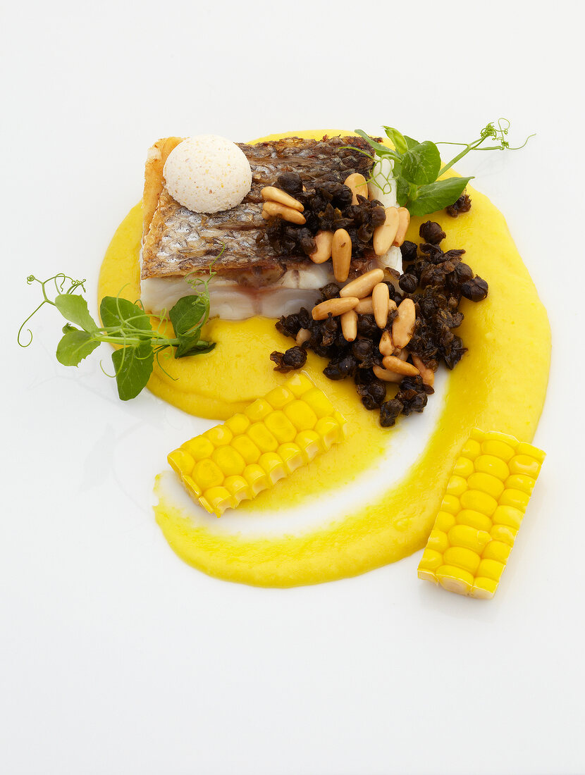 Perch with sweet corn, capers and pine nuts on white background