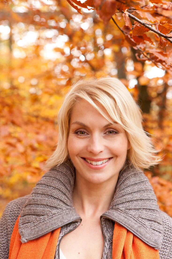 Portrait of pretty blonde woman with short hair wearing gray sweater, smiling