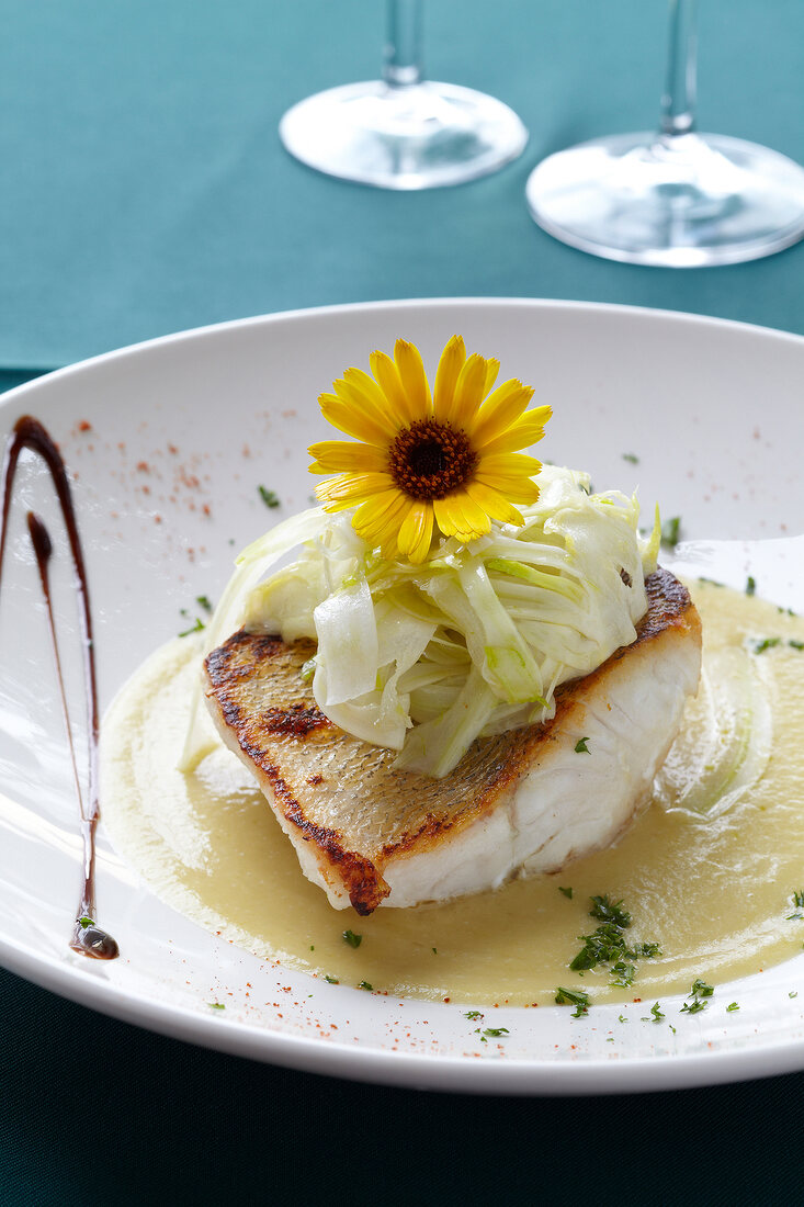 Zander with fennel sauce garnished with fennel and flower on plate