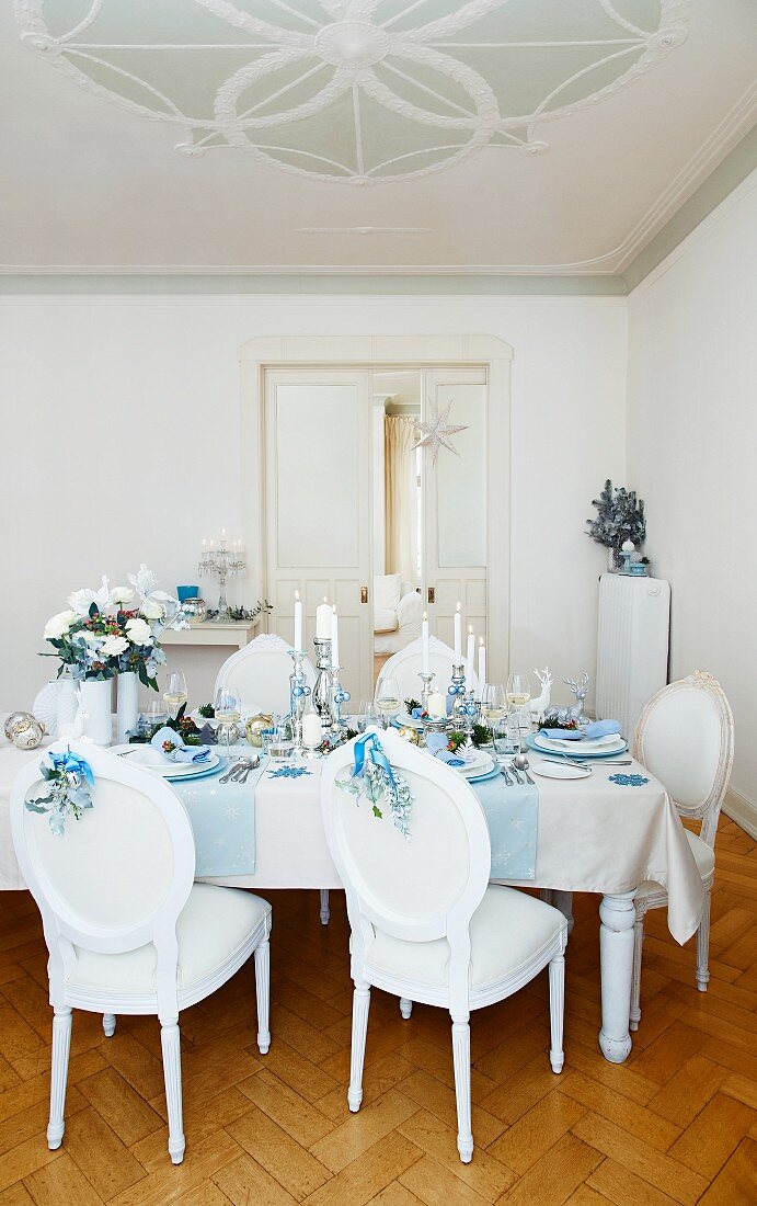 A table laid for Christmas dinner decorated in sliver, blue and white