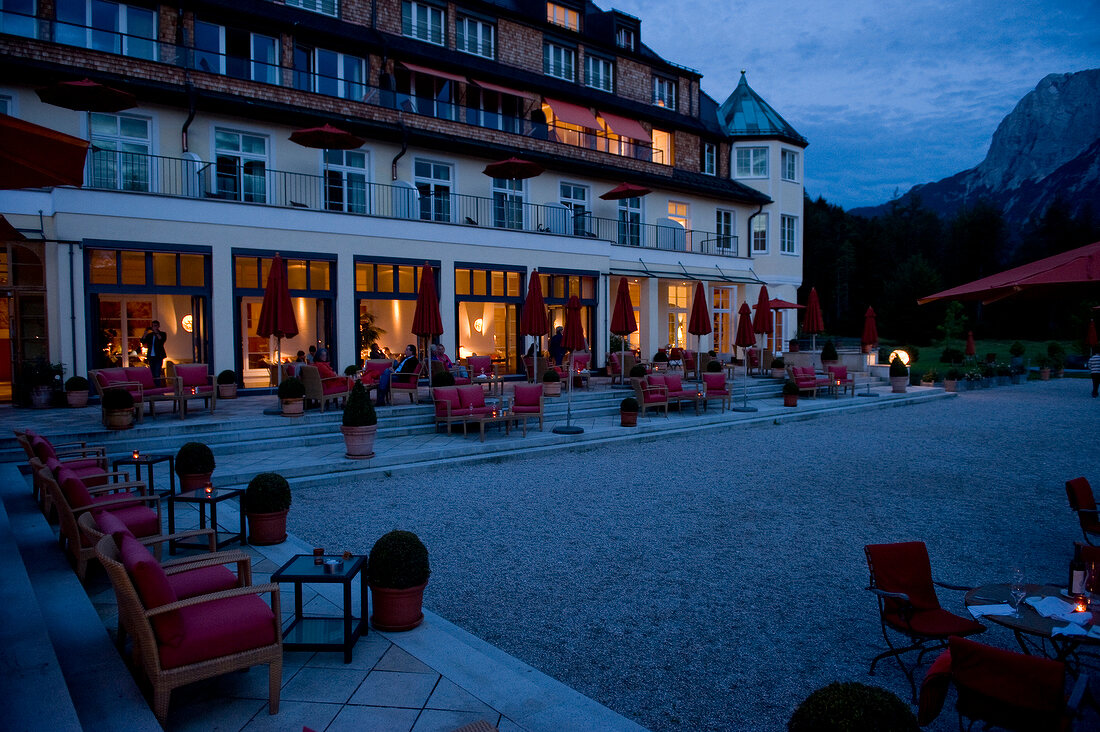 People sitting in terrace of Hotel Schloss Elmau at dusk, Upper Bavaria, Germany