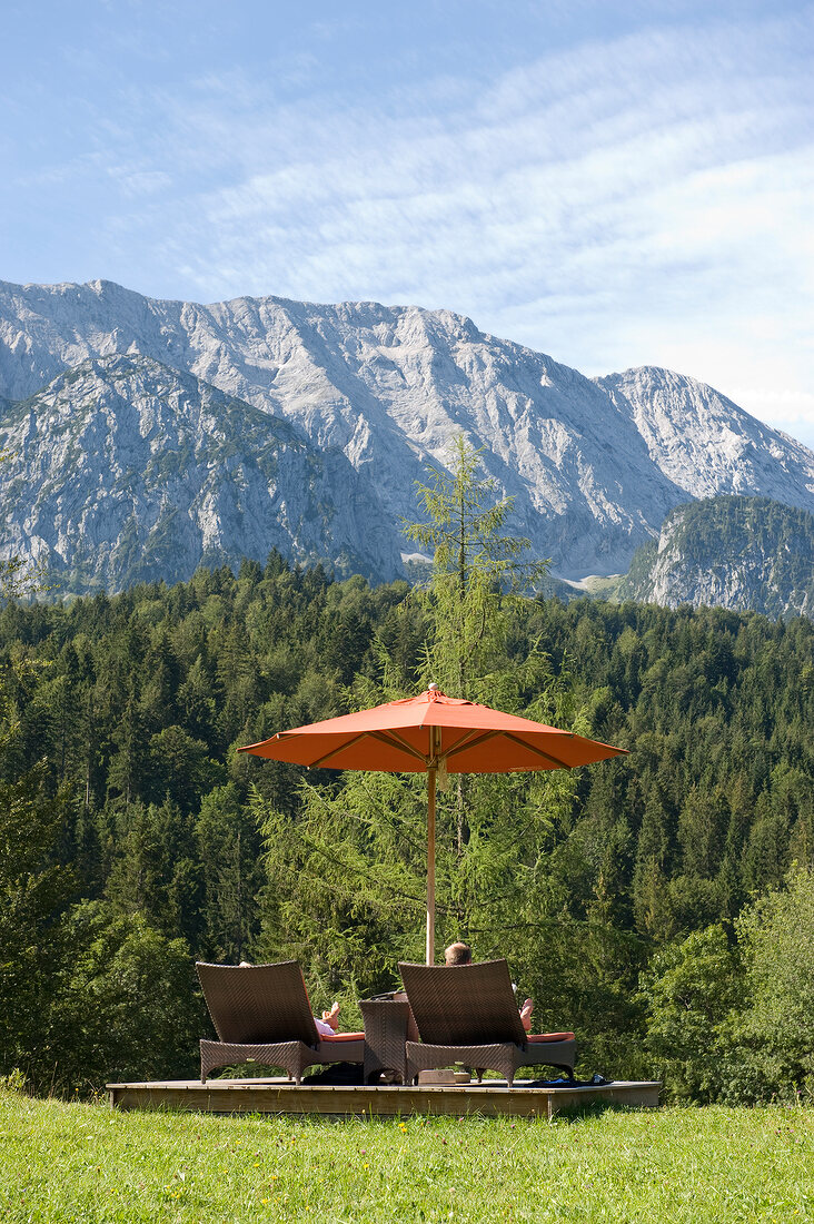 Loungers in garden of Hotel Schloss Elmau overlooking mountains, Upper Bavaria, Germany