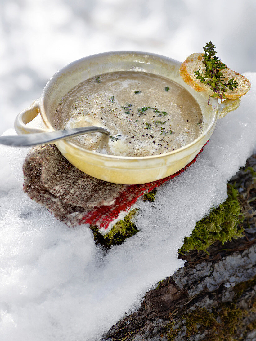 Chestnut cream soup with thyme and baguette in bowl for winter
