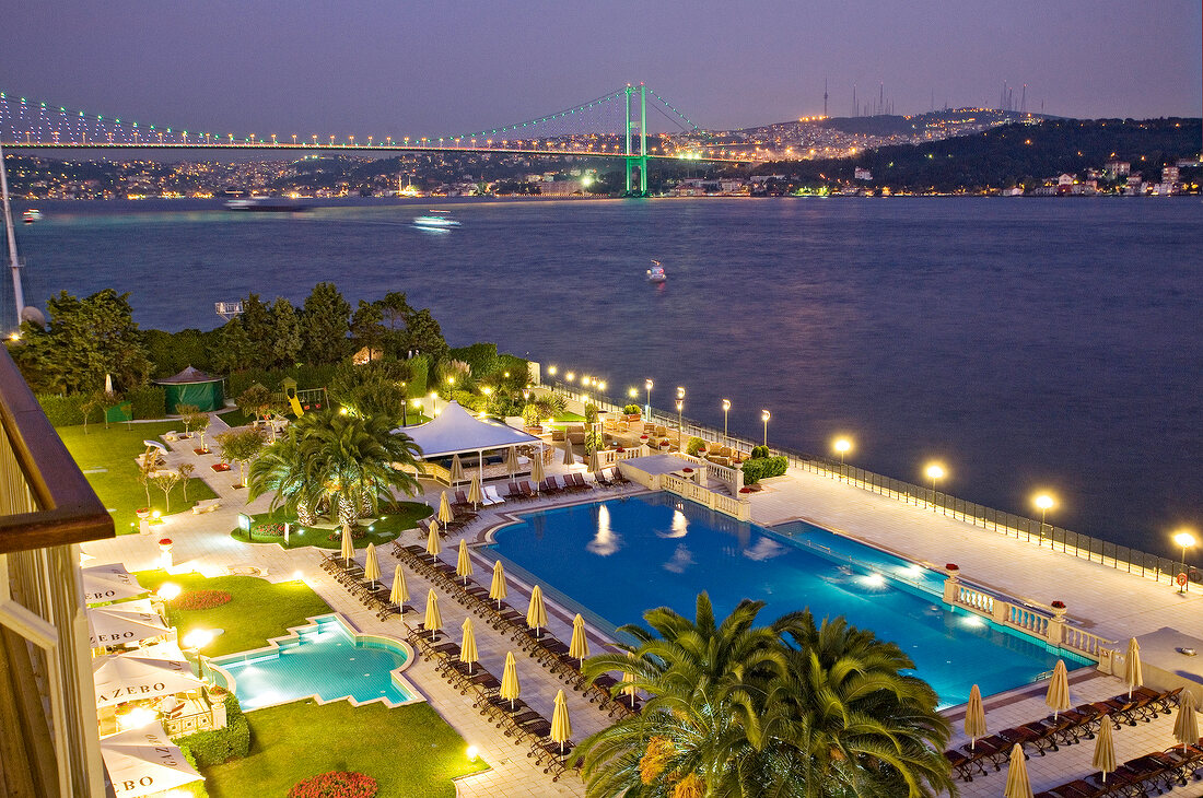 View of swimming pool of Ciragan Palace Kempinski and Bosphorus bridge at night, Istanbul