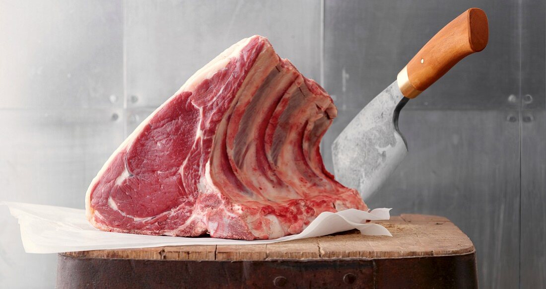 Raw cote de boeuf with a knife in a wooden block