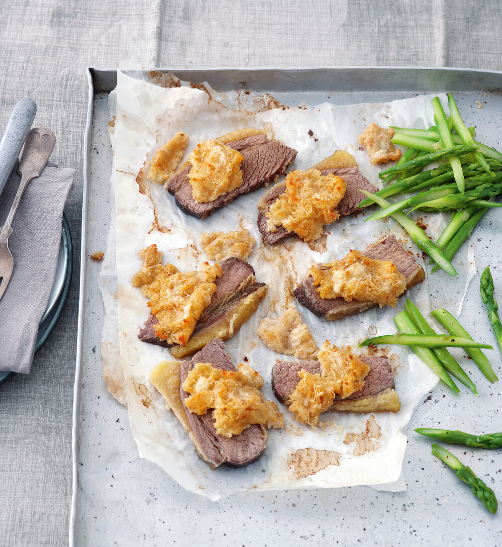 Close-up of beef brisket with cheese crust on baking sheet