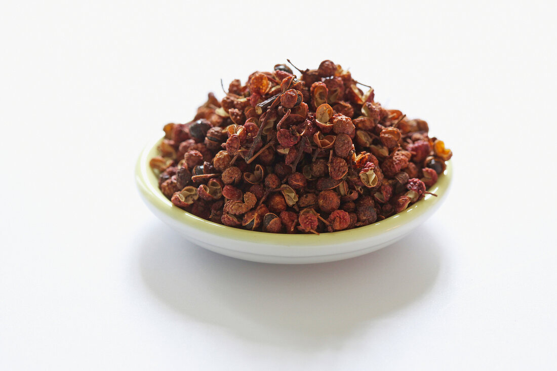 Szechuan pepper in bowl on white background