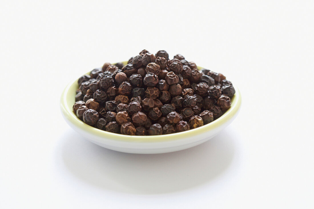 Tellicherry pepper in bowl on white background