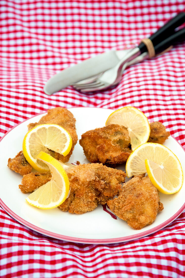 Chicken wings with baked slices of lemon on plate