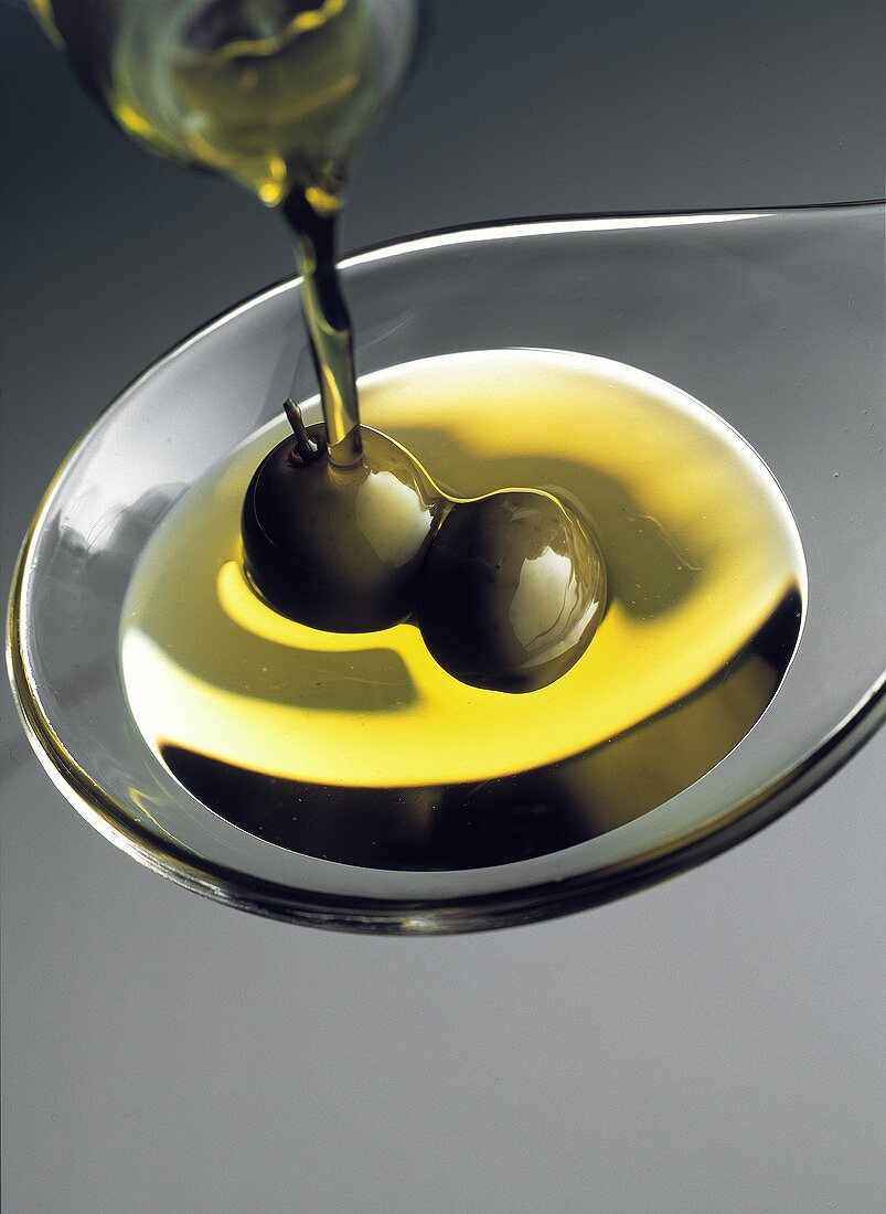 Pouring Olive Oil onto Spoon with Olives