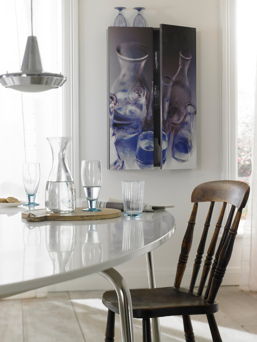 Close-up of table with chair, glasses and closet on wall