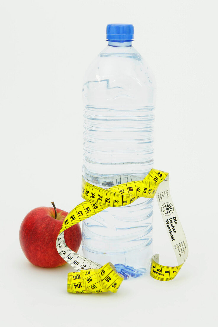 Symbolbild für Diät, Flasche Wasser mit Maßband und roter Apfel