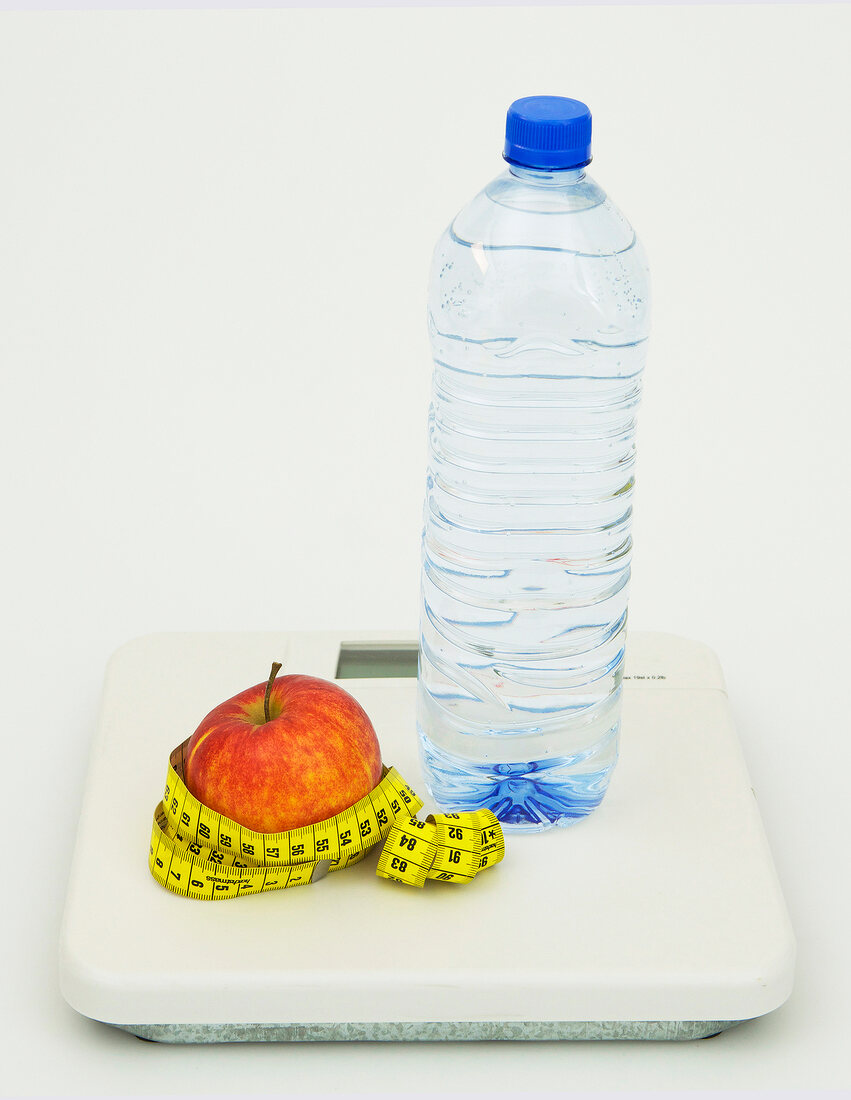 Symbolbild für Diät, Apfel mit Maßband und Wasser auf Waage