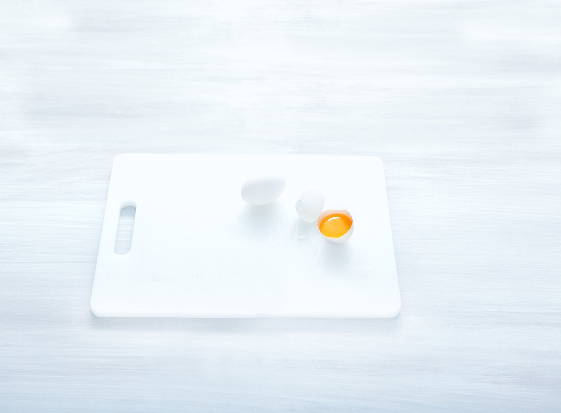 Egg yolk and egg shell on white chopping board