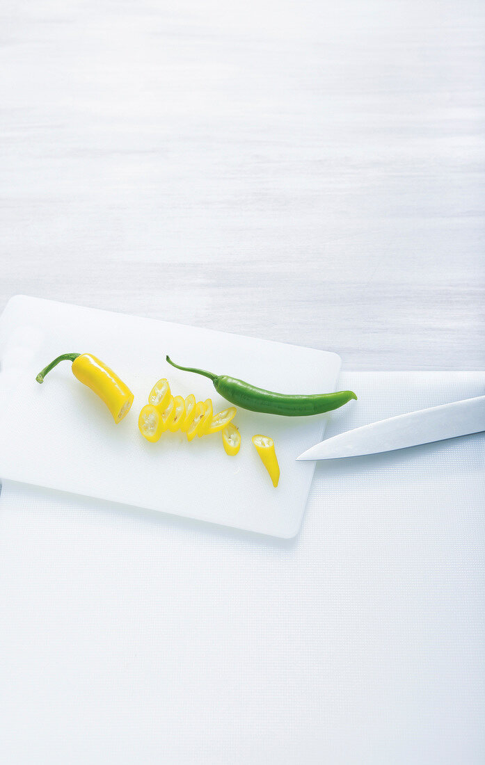 Yellow and green chilli peppers on cutting board