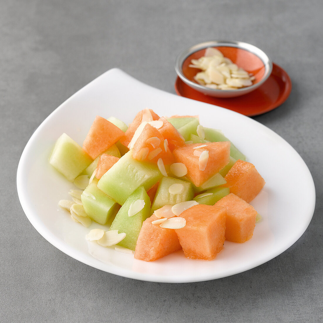 Melon salad with flaked almonds on plate