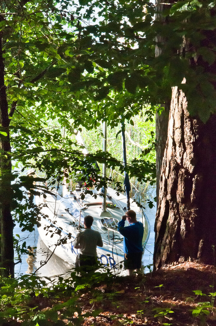 Two man looking at moored boat, Masurian Lake District, Mikolajki, Warmia Masuria, Poland