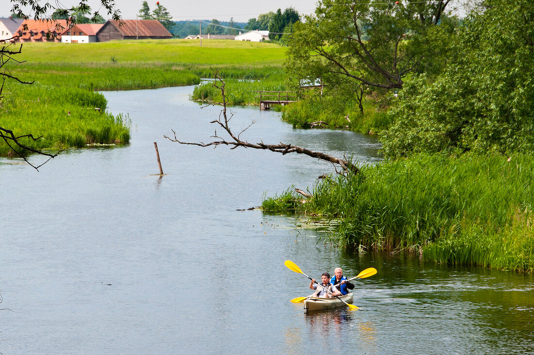 Men canoeing in lake while passing through Ukta in Ruciane-Nida, Warmia-Masuria, Poland