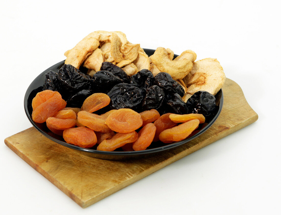 Plate of various dried fruits on white background