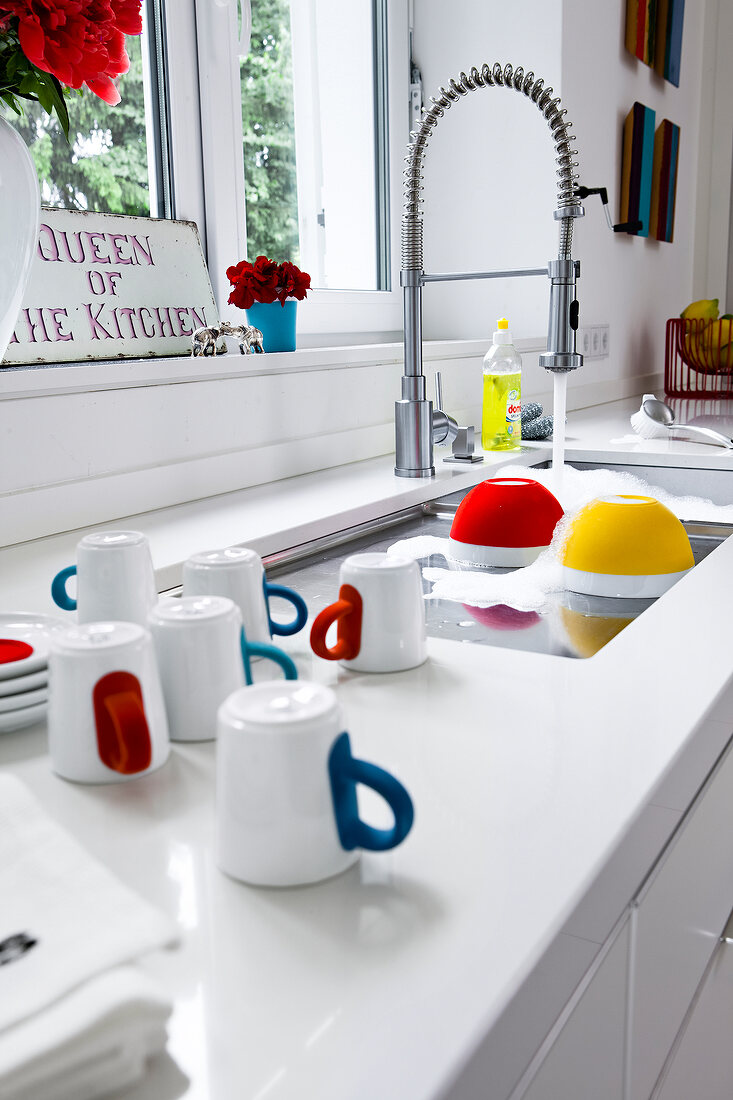 Water flowing in sink with dishes around