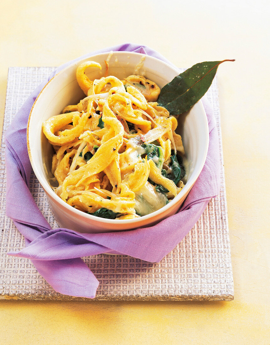 Spaetzle pasta with cheese and fonduta cream in ceramic bowl